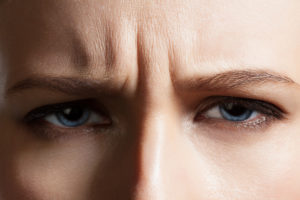 Angry face of a young woman with facial wrinkles closeup